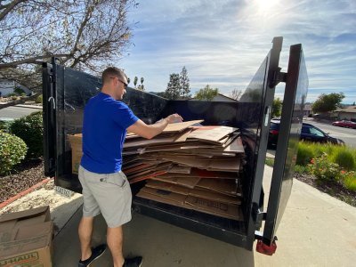 Junk removal professional loading junk debris into a trailer during a residential cleanup project in San Marcos, CA